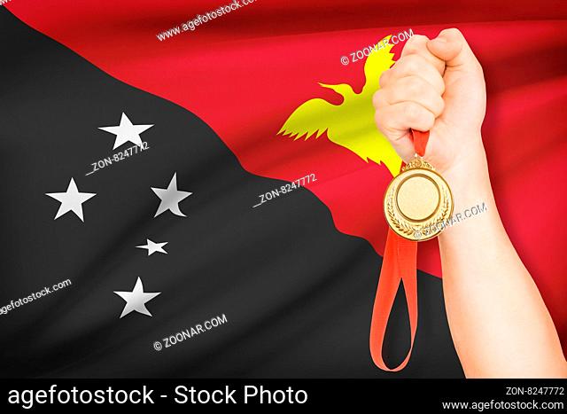 Sportsman holding gold medal with flag on background - Independent State of Papua New Guinea