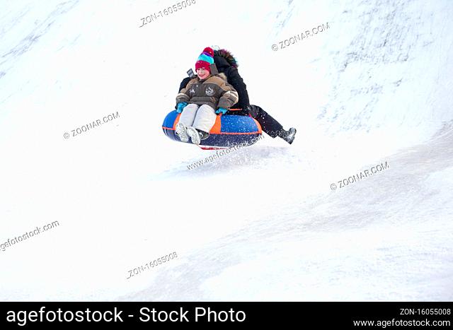 Child sledding cheesecake.Sledding off a snow slide.Ski jumping on tubing. Winter children's holiday