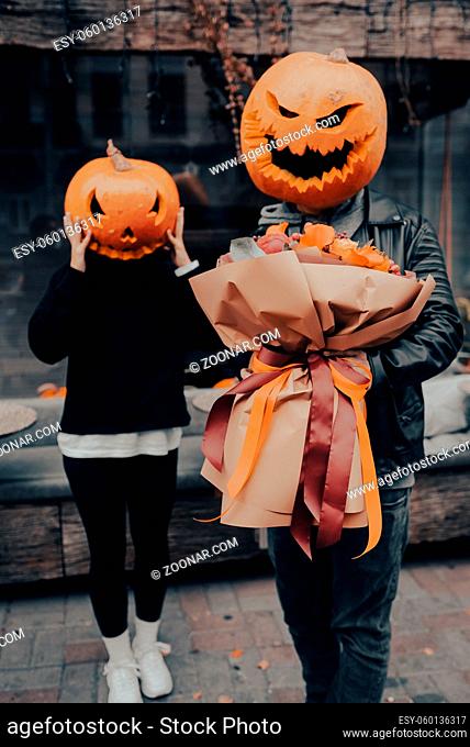 The guy gives his girlfriend a bouquet, both with a pumpkin head. Halloween Concept