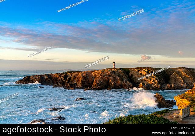 view of the rugged Alentejo coastline and Porto Covo lighthouse at sunset