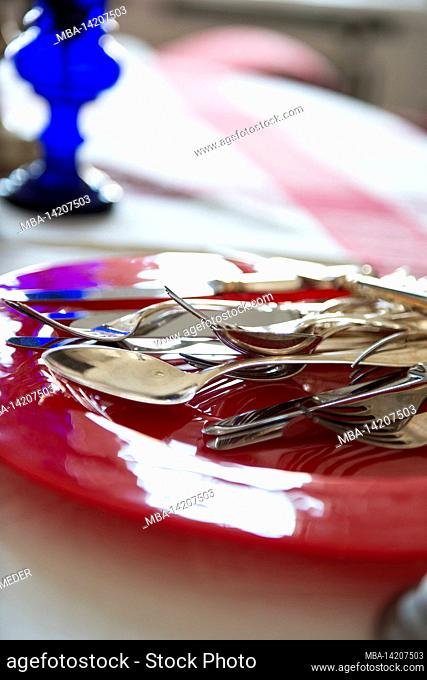 Cutlery, red glass plate, knife, fork and spoon