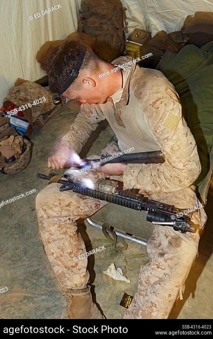 A U.S. Marine Maintains his M4 Carbine at a Small Combat Outpost in Afghanistan's Helmand Province