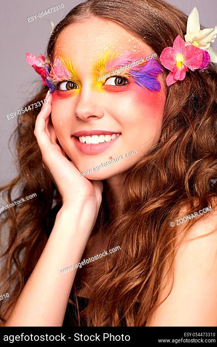 Portrait of happy smiling teen girl with hand near face. Young female with unusual stylish make-up and false fashion feather eyelashes