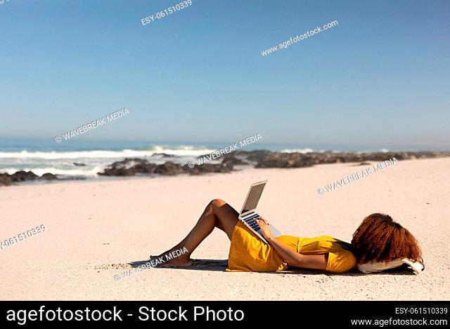 Mixed race woman using computer on the beach