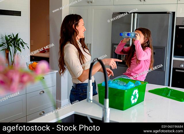 Happy caucasian mother and daughter segregating rubbish