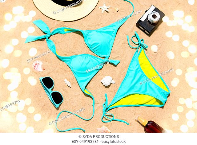 bikini, hat, camera and sunglasses on beach sand