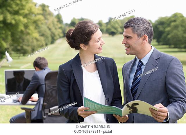 Business people looking at report together outdoors