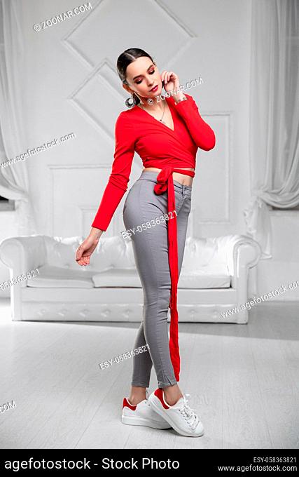 Charming lady dressed in a red blouse and jeans posing in the studio