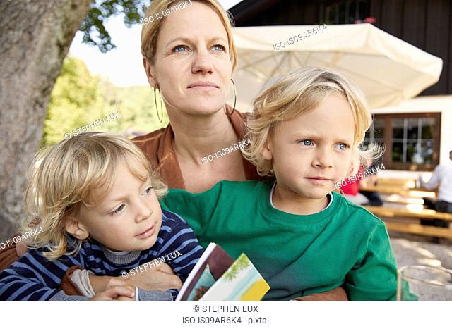 Mother and two sons sitting together, outdoors