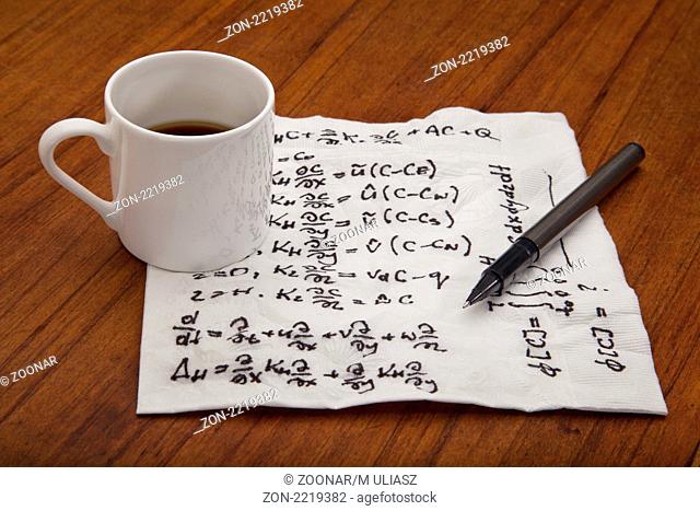 mathematical equations of physics - handwriting on a napkin with espresso coffee cup on table