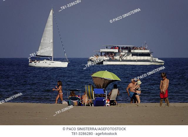 People on the beach with boats on background. Malvarrosa Beach, Valencia, Spain