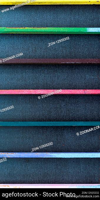 Colorful metal bars in front of a black background in close-up