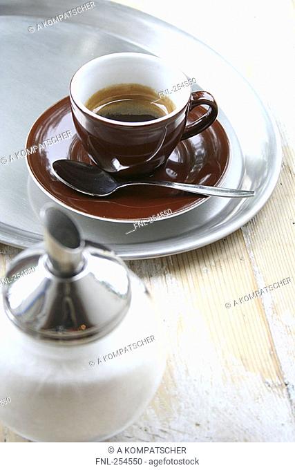 High angle view of cup of black coffee and sugar shaker