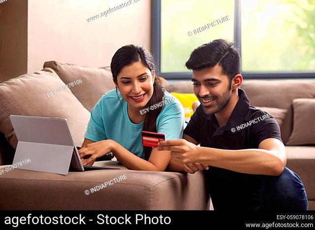 A girl with laptop and a boy with credit card shopping online