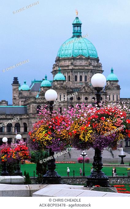 Flower baskets hanging from lamp posts with the Parliament buildings beyond, Victoria, Vancouver Island, British Columbia, Canada