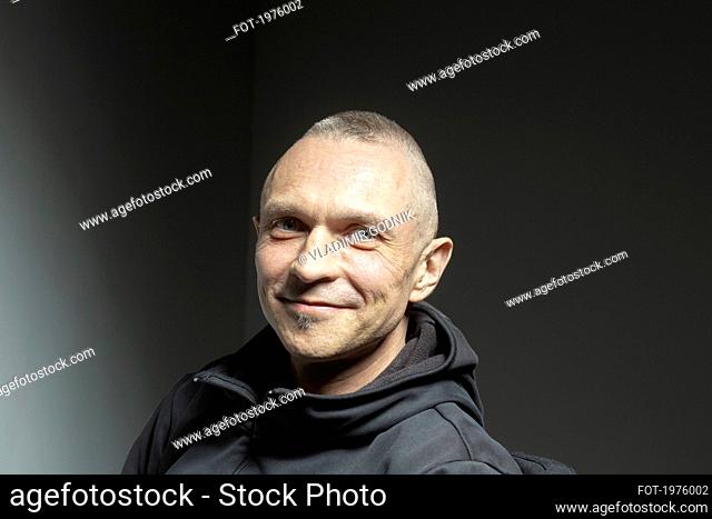 Portrait confident handsome man smiling on black background