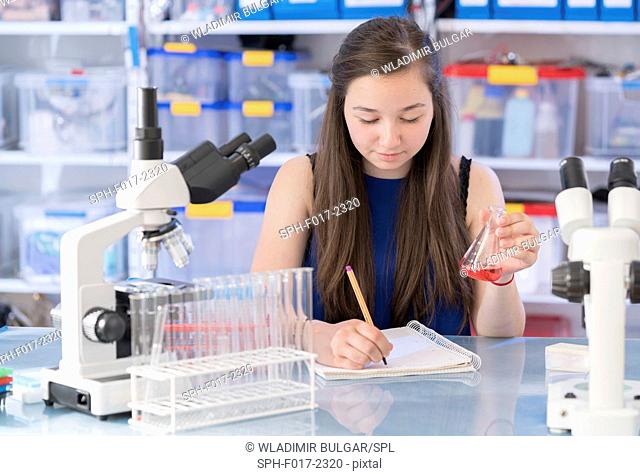 MODEL RELEASED. Girl making notes in laboratory