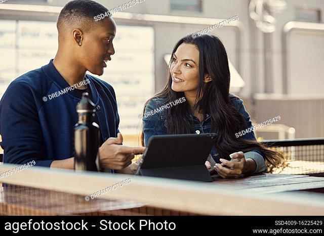 Portrait of young people working on a tablet at an outdoor cafe