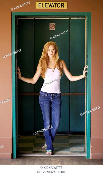 A young woman stands in the open doors of an elevator, kauai hawaii united states of america