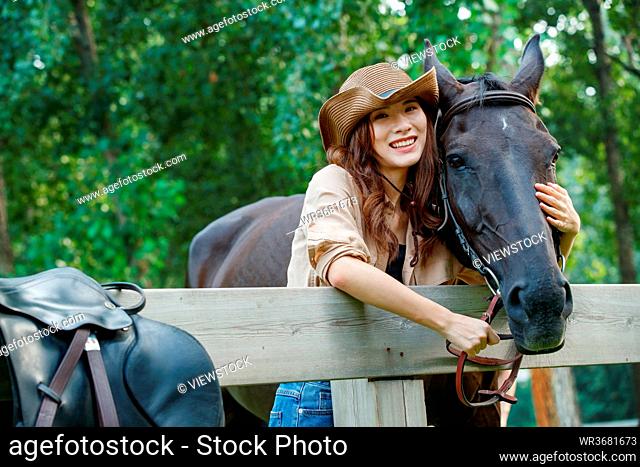 Happy young woman of outdoor arm around the horse