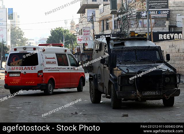 12 December 2023, Palestinian Territories, Jenin: Israeli security forces search a Palestinian ambulance at a hospital entrance during a raid at the Jenin...