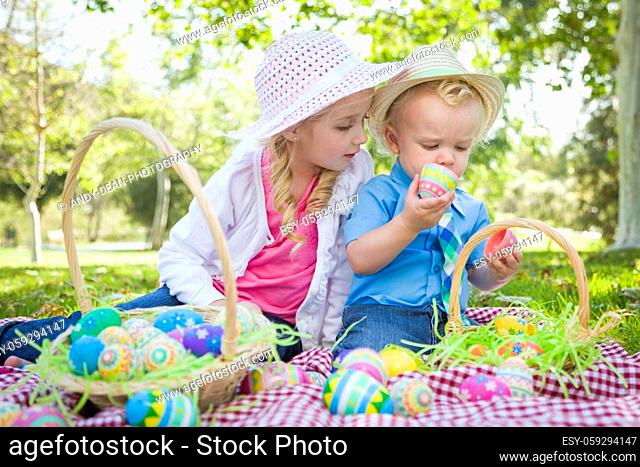 Cute Young Brother and Sister Enjoying Their Easter Eggs Outside in the Park Together