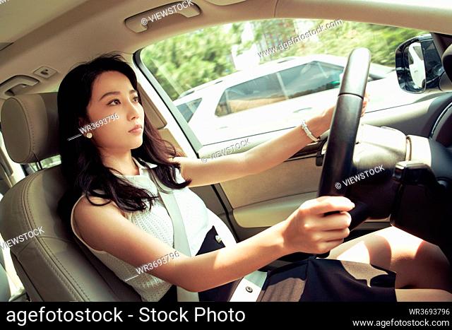 A beautiful young woman driving a car