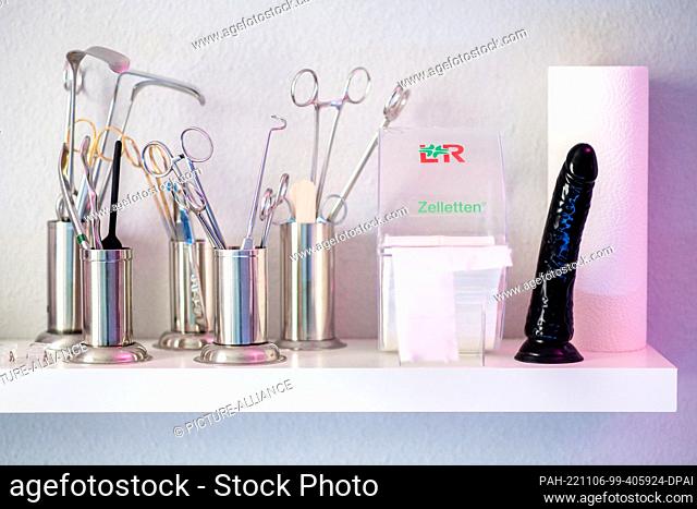 06 November 2022, Lower Saxony, Oldenburg: A black dildo and doctor's cutlery stand on a rule in the clinic room in a studio