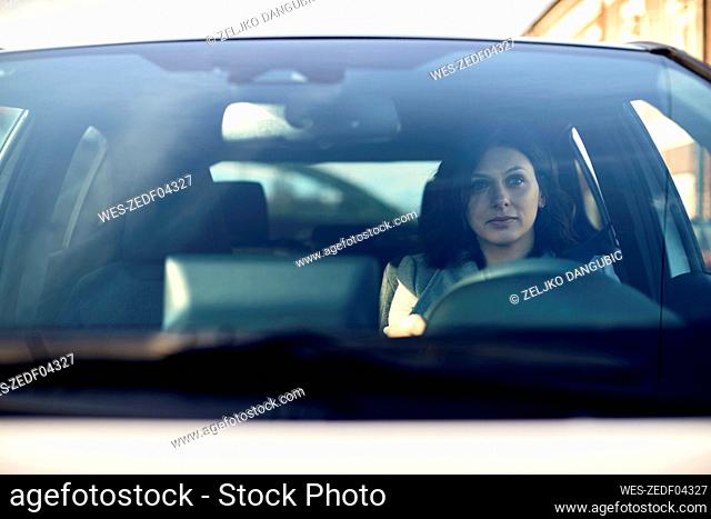 Woman driving electric car seen through windshield