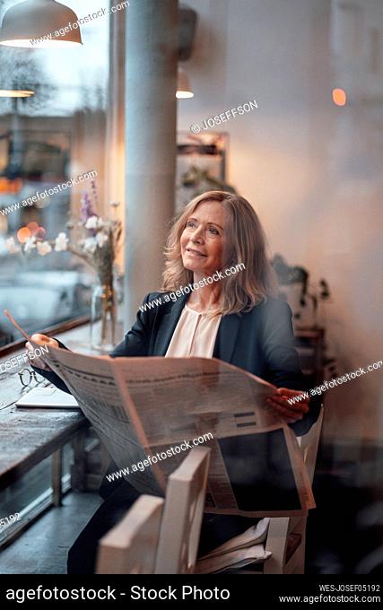 Blond businesswoman sitting with newspaper in cafe