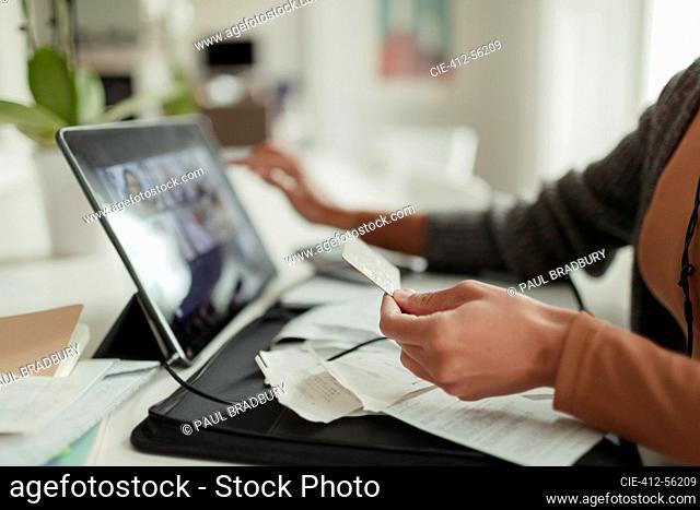 Close up woman with credit card paying bills at digital tablet