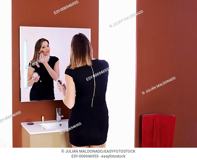 Beautiful young woman applying makeup in the bathroom