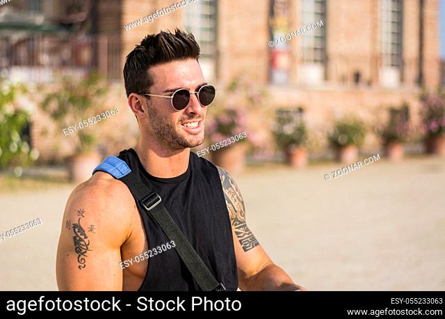 Handsome muscular man with tattoo posing in European luxury garden at Venaria Reale royal palace near Turin, Italy