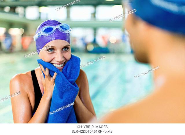 Swimmer toweling off her face by pool