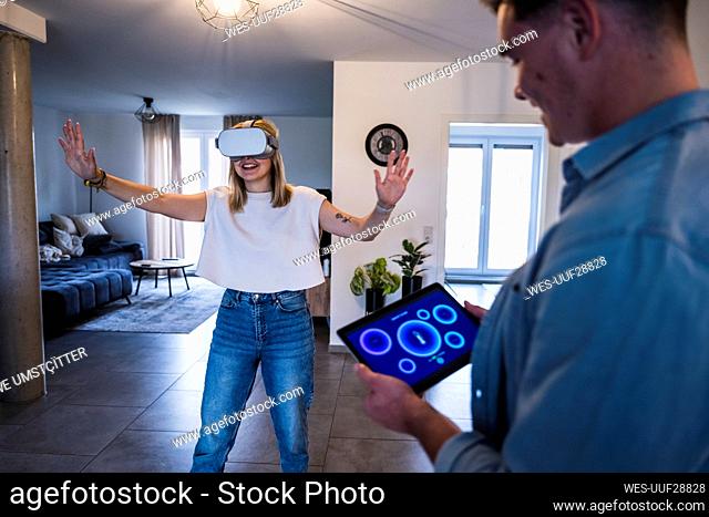 Man using tablet PC with woman wearing virtual reality simulator