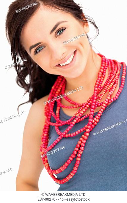 Blue eyed brunette posing with a red bead necklace against white background