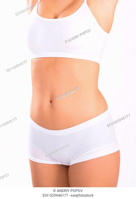 Midsection of young woman in innerwear standing over white background