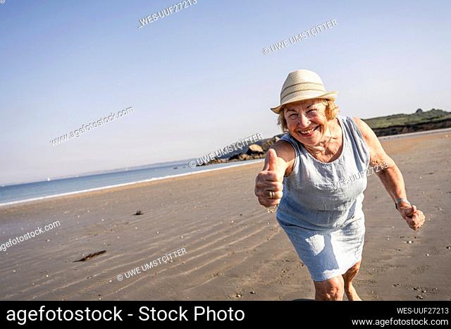Happy senior woman showing thumbs up at beach