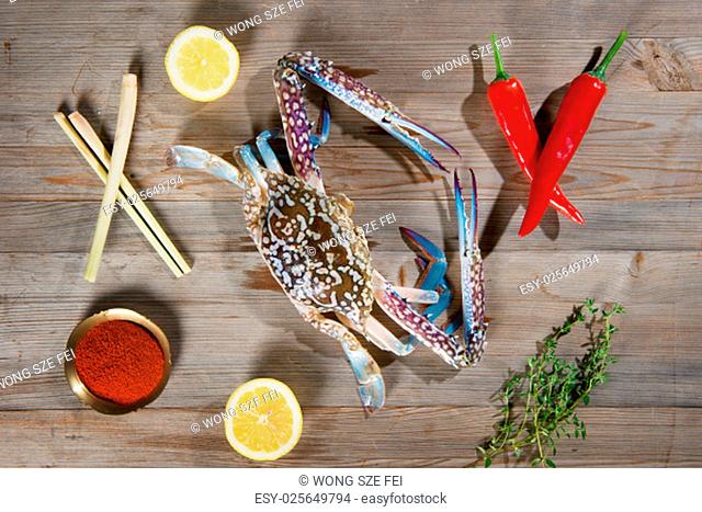 Top view raw blue crab and ingredients ready to cook, on wood background
