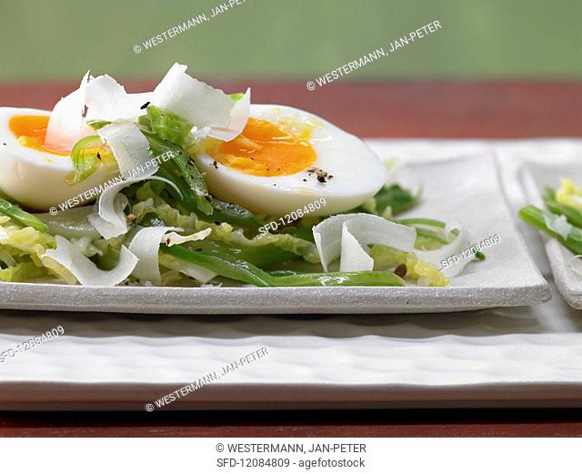 Medium-soft (waxy) boiled eggs on a bed of savoy cabbage and beans
