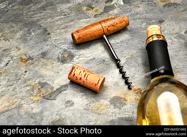 Top view of a wine bottle and cork screw on a slate surface