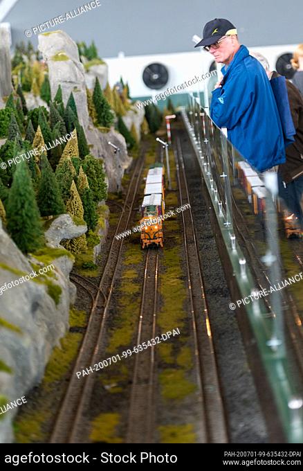 01 July 2020, Lower Saxony, Bispingen: A visitor looks at a passing train on the model railway layout. A total of 500 trains are to roll through various theme...