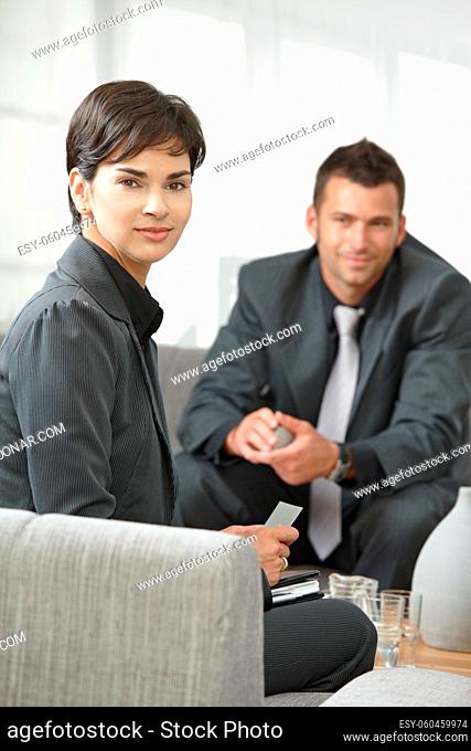 Business meeting at office lobby, young attractive businesswoman looking at camera, smiling