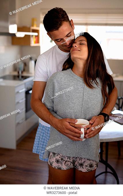 Romantic couple standing with arm around while having cup of coffee