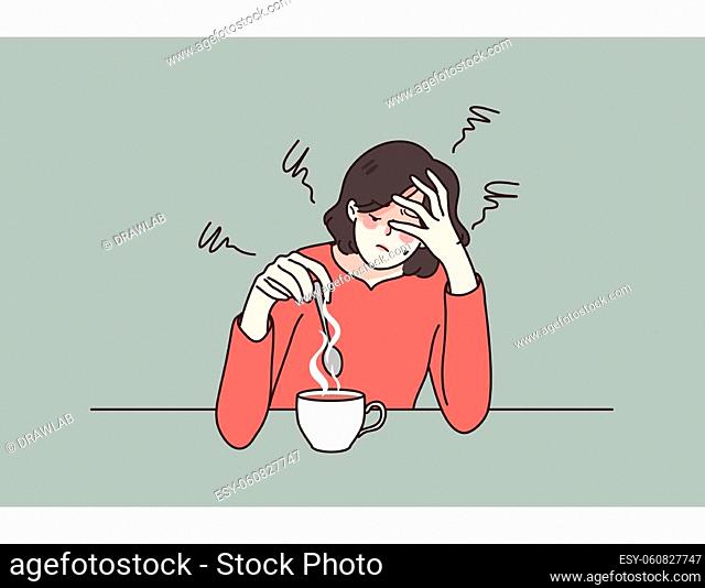 Exhausted young woman sit at table drink coffee feel fatigue or drowsiness. Tired female suffer from overwork lack energy need caffeine