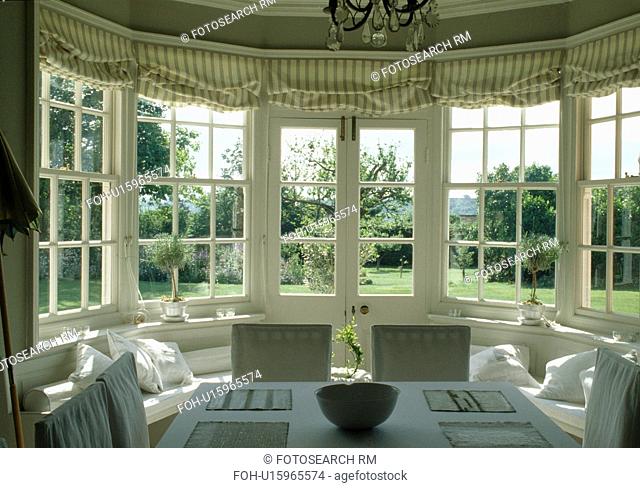 Striped blinds on French windows in dining room with view of the garden
