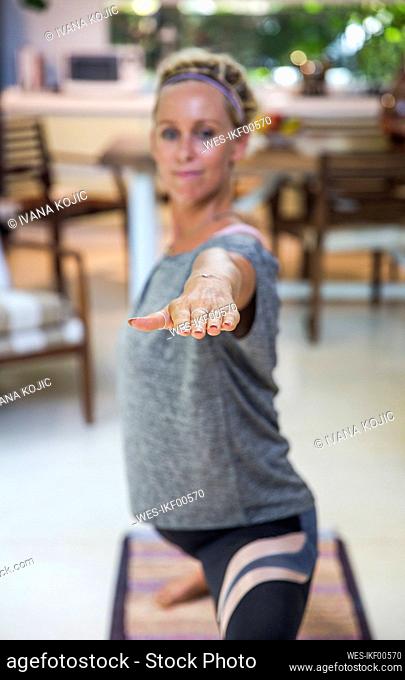 Woman doing Warrior 2 pose at home