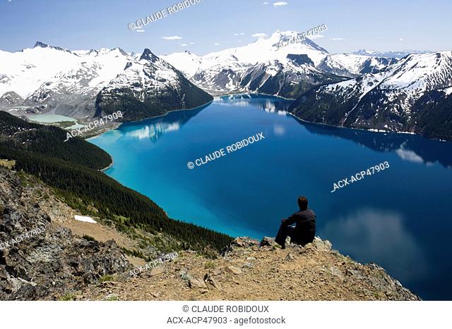 Hiker on top of Panorama Ridge over looking Garibaldi Lake in Garibaldi Provincial Park between the towns of Squamish and Whistler in British Columbia, Canada
