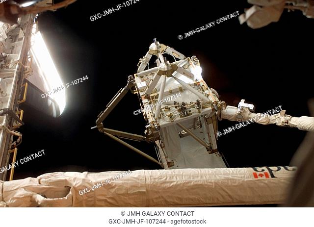The International Space Station's new P5 truss section is moved out of Space Shuttle Discovery's payload bay by a cabin-bound STS-116 crewmember