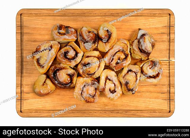 Top view of glazed cinnamon rolls buns on wooden plate isolated over white background
